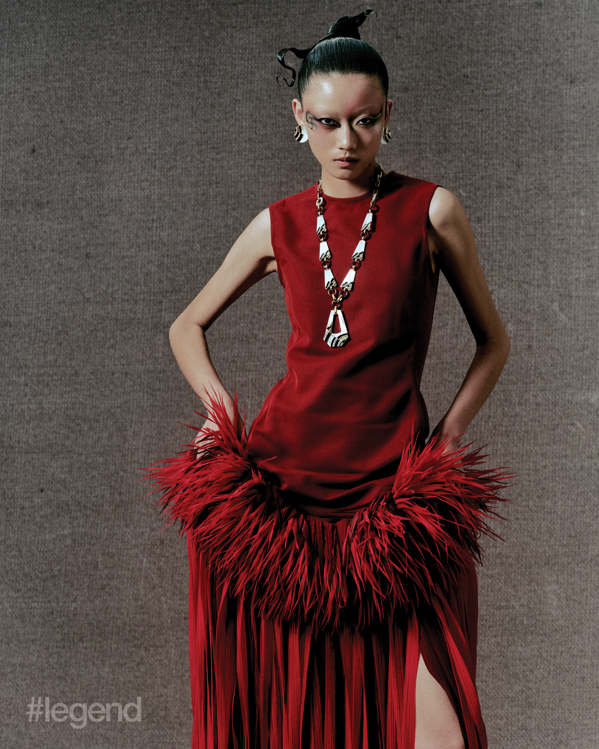 Red dress with feathers _ Bottega Veneta; Heritage Collection necklace in platinum and yellow gold with black enamel, white mother-of-pearl, carnelian and diamonds; and earrings in platinum and yellow gold with black enamel, white mother- of-pearl and diamonds _ Van Cleef & Arpels