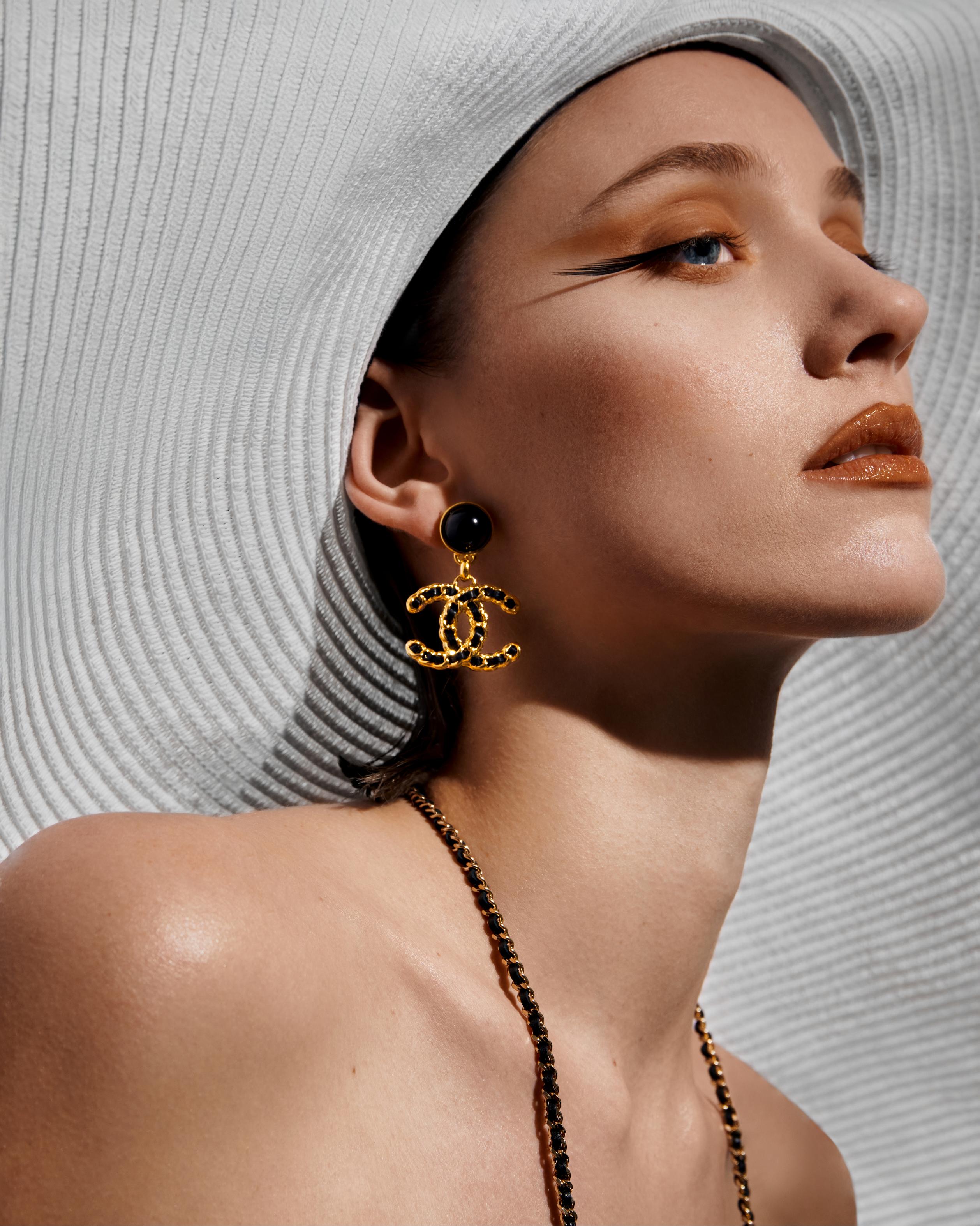  Braided earrings and necklace _ Chanel; White wide-brim hat with crystal pin _ Chanel