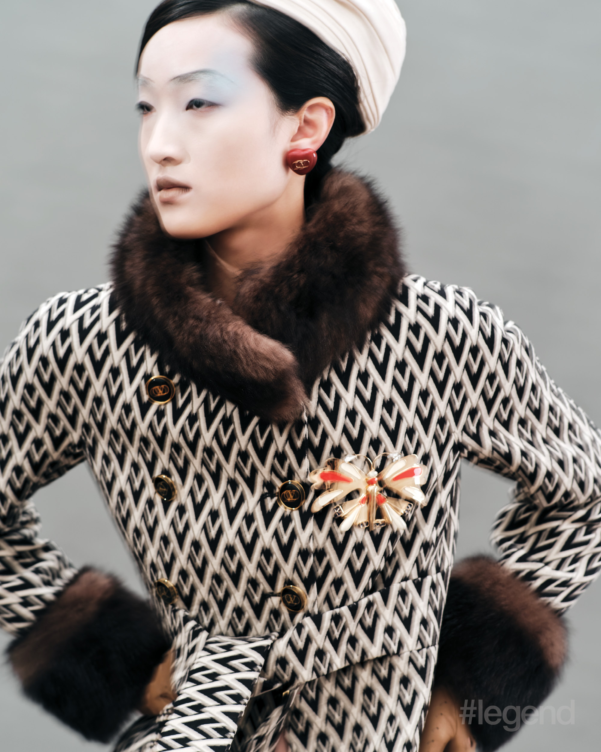 Black and white faux fur-trim coat, white head wrap, red heart earrings and dragonfly brooch _ Valentino