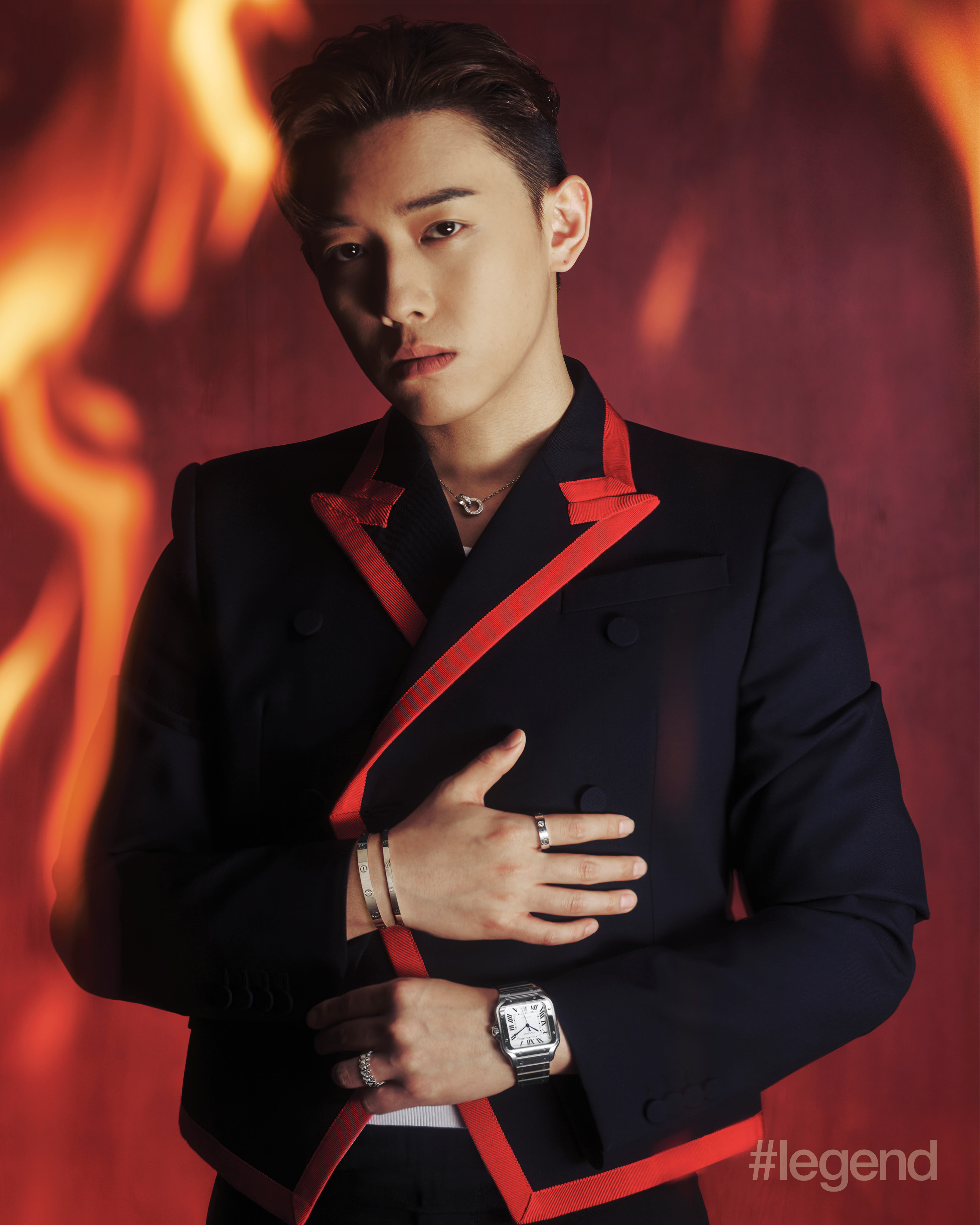 Cartier Love necklace in white gold with diamonds, bracelets in white gold, and ring in white gold with diamonds; Clash de Cartier ring in white gold and Santos de Cartier watch in steel _ Cartier; Navy jacket with red trim and flared trousers _ McQueen